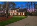 Gorgeous two-story brick home at dusk, featuring a manicured lawn and welcoming driveway at 4165 Liberty Trce, Marietta, GA 30066