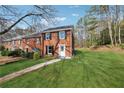 Side view of a brick two-story home with a spacious yard and mature trees at 185 Willow Stream Ct, Roswell, GA 30076