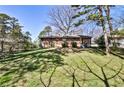 A view of the backyard with green grass, trees, and the back of a brick single story home at 1949 Capri Dr, Decatur, GA 30032