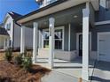 Inviting covered front porch with white columns, brick accents, and view of the house number at 2724 Mourning Dove Drive Lot 32, Grayson, GA 30017
