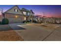 Exterior of a large home at dusk featuring a long driveway and meticulously maintained landscaping at 257 Lakestone Pkwy, Woodstock, GA 30188