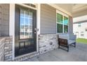 Inviting covered front porch with chair, brick base and decorative front door with sidelights at 140 Worthing Ln, Fairburn, GA 30213