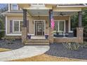 Inviting covered porch with brick supports, comfortable seating, and an American flag at 3207 Kensington Rd, Avondale Estates, GA 30002