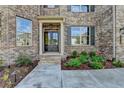 Elegant entryway featuring a black front door with sidelights, brick steps, and landscaped garden beds at 5533 Addison Woods Pl, Buford, GA 30518