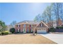 Charming brick home features a manicured lawn, attached two-car garage, and beautiful, mature landscaping at 6820 Olde Atlanta Pkwy, Suwanee, GA 30024