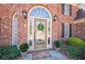 Up close front exterior of brick house with arched glass door and sidelights, potted plants and welcome mat at 6820 Olde Atlanta Pkwy, Suwanee, GA 30024