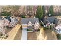 Aerial view of a traditionally styled home with a long driveway, situated amongst mature trees and neighboring houses at 675 Timber Ives Dr, Dacula, GA 30019