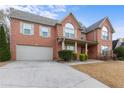 Charming two-story brick home featuring an attached garage, a welcoming front porch, and neat landscaping at 675 Timber Ives Dr, Dacula, GA 30019
