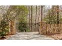 Stone and wrought iron entry gate securing a driveway on a wooded property at 5150 Rockford Ln, Stockbridge, GA 30281