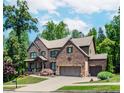 Beautiful two-story brick home featuring a landscaped lawn and a three-car garage at 1351 Ashbury Park Dr, Hoschton, GA 30548