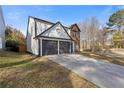 Side view of a two-story home featuring a two-car garage and a well-maintained lawn at 1074 Wenham Ln, Lawrenceville, GA 30044