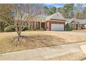 Classic brick home showcasing a manicured lawn, a two-car garage, and inviting front entrance with a charming porch at 564 Grand Ashbury Ln, Sugar Hill, GA 30518