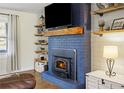 Living room fireplace with a blue brick surround, a wood mantle, and floating shelves at 5320 Karr Rd, Cumming, GA 30040