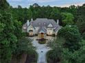 Expansive home featuring manicured landscaping, a circular driveway, and a grand entrance amidst mature trees at 510 Covington Cv, Alpharetta, GA 30022