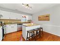 Cozy kitchen with hardwood floors, white cabinetry, granite countertops, stainless steel appliances, and a convenient island at 216 Tennis Court Nw Ln, Kennesaw, GA 30144