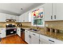 Bright kitchen features hardwood floors, white cabinetry, granite counters, and stainless steel appliances at 216 Tennis Court Nw Ln, Kennesaw, GA 30144
