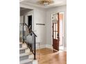 Bright foyer featuring hardwood floors, staircase with iron railing, and view of the front door at 321 Mado Ln, Chattahoochee Hills, GA 30268