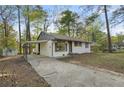 Side view of a white brick home, featuring a carport and long driveway at 7323 Howard Pl, Jonesboro, GA 30236