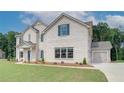 Side view of a two-story white brick home, showcasing the attached two-car garage and manicured lawn at 193 Haverling Pass, Hampton, GA 30228