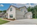 Attached three-car garage with concrete driveway and the side and rear of the white brick home at 193 Haverling Pass, Hampton, GA 30228