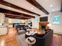 Inviting living room open to the kitchen featuring exposed beams, a fireplace and hardwood floors at 973 Peachtree Battle Ave, Atlanta, GA 30327