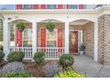 Close-up of the inviting front porch with hanging plants, red shutters, and a wooden front door at 3641 Devenwood Way, Buford, GA 30519