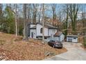 Gray home with a chimney, vertical siding, a curved window, and a shed on a wooded lot at 1291 Marcelle Heights Pl, Norcross, GA 30093