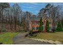 Expansive front yard featuring a paved driveway with steps to the traditional brick home and its manicured landscaping at 2070 Sweetgum Trl, Cumming, GA 30041