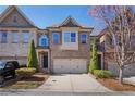 Charming brick townhome featuring a two-car garage, manicured landscaping, and mature trees at 7630 Glisten Ave # 304, Atlanta, GA 30328
