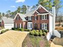 Beautiful brick home featuring a manicured lawn, complementing shrubs, and black window shutters at 2046 Woodside Park Dr, Woodstock, GA 30188