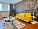 Inviting living room with a bright yellow sofa, unique patterned wallpaper, and hardwood floors, providing a comfortable atmosphere at 215 Piedmont Ne Ave # 602, Atlanta, GA 30308