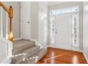 Bright entryway with hardwood floors, carpeted stairs, and natural light from sidelight windows at 4677 Creekside Cv, Atlanta, GA 30349