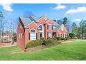 A charming side view of a two-story red brick home with a well-manicured lawn at 325 Stonecastle Pass, South Fulton, GA 30331