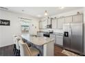 Modern kitchen with granite countertops, stainless steel appliances, island with bar stools, and wood flooring at 201 Cranapple Ln, Mcdonough, GA 30253