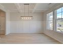 Bright dining room with modern light fixture, coffered ceiling, wainscoting, and hardwood floors at 400 Hatcher Ct, Hampton, GA 30228