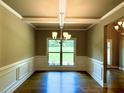 Elegant dining room with tray ceiling, wainscoting, modern chandelier, and a large window at 125 Honey Creek Rd, Conyers, GA 30094