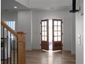 Bright foyer featuring wood floors, a staircase with iron railings, and open double doors at 115 River Meadow Ln, Social Circle, GA 30025