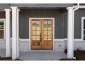 Inviting front entryway featuring double wooden doors with glass panels and classic white columns at 115 River Meadow Ln, Social Circle, GA 30025