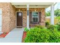 Inviting front porch with brick accents, a cozy bench, and well-maintained landscaping at 3391 Meadow Grass Dr, Dacula, GA 30019