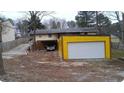View of the detached two-car garage with a driveway leading to additional parking beneath the elevated house structure at 4574 Cedar Ridge Trl, Stone Mountain, GA 30083