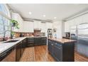 Modern kitchen with white upper cabinets, black lower cabinets, an island, stainless steel appliances, and brick backsplash at 2883 Misty Rock Cv, Dacula, GA 30019