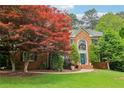 Charming brick home featuring a manicured lawn, mature trees, and inviting blue door at 828 Guinevere Sw Way, Lilburn, GA 30047