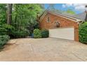 Side view of brick house showing garage with basketball hoop and driveway at 828 Guinevere Sw Way, Lilburn, GA 30047