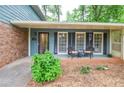 Inviting covered front porch with seating area, brick accents, and attractive curb appeal at 1438 Ridgeland Sw Ct, Lilburn, GA 30047