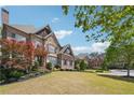 Beautiful brick and stone home with landscaped front yard, mature trees, and driveway on a sunny day at 1655 Dawn Dr, Suwanee, GA 30024