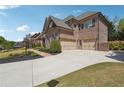 Exterior view of a brick home featuring a three-car garage and a paved driveway with grass lawn at 1655 Dawn Dr, Suwanee, GA 30024