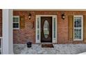 Elegant front door with sidelights and decorative glass, framed by brick and sconce lighting at 1915 Turtle Creek Way, Lawrenceville, GA 30043