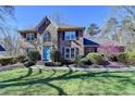 Attractive brick home showcasing a bright blue front door and beautiful, mature landscaping at 2030 Habersham Trce, Cumming, GA 30041