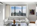 Bright living room featuring a plush white sofa, modern furnishings, and a large window offering panoramic city views at 75 14Th Ne St # 3430, Atlanta, GA 30309