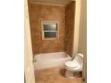 Bright bathroom features neutral tile surround, a window, and a bathtub with shower at 1415 Dodson Sw Dr, Atlanta, GA 30311